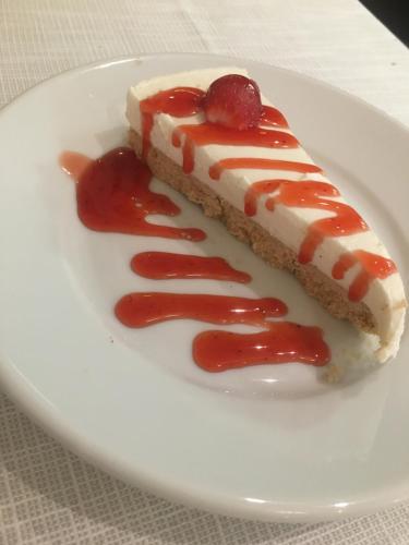 a piece of cake with strawberry sauce on a white plate at Hotel Bellevue in Lignano Sabbiadoro