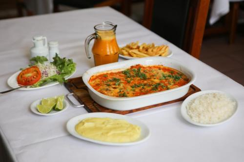 a table topped with a dish of food and other foods at Hara Palace Hotel in Curitiba