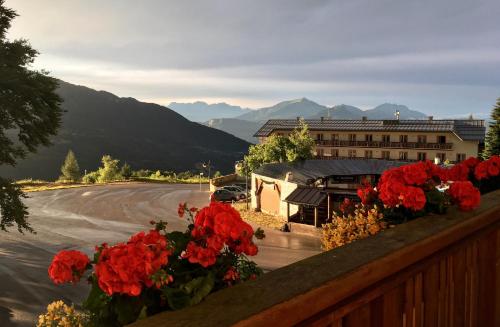 uma vista para um edifício com flores vermelhas numa cerca em Etrusca Polsa em Brentonico