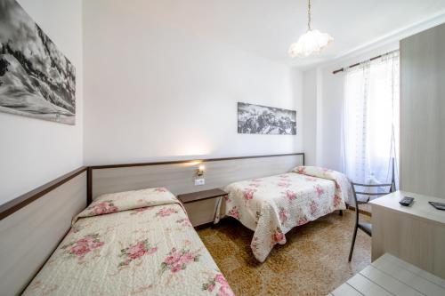 a bedroom with two beds and a desk and a window at La Belle Epoque in Aosta