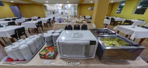 a restaurant with a counter with a microwave and food at Hara Palace Hotel in Curitiba