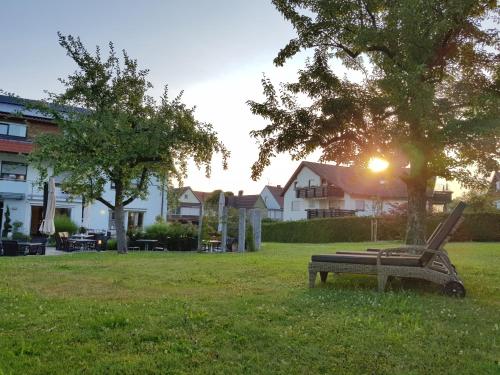 a park bench sitting in the grass under a tree at Landhotel Sonnenhalde in Bad Boll