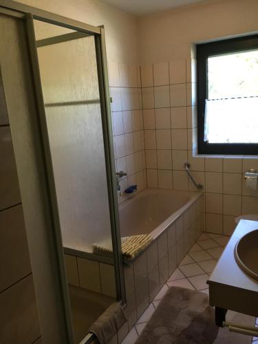 a bathroom with a bath tub and a window at VormHolte in Radevormwald