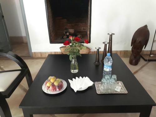 a black table with a plate of fruit and a bottle of water at Riad Tchaikana in Marrakech