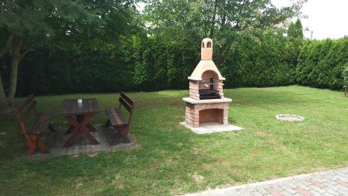 a small brick grill in a yard with a table and benches at Anna villa in Lenti