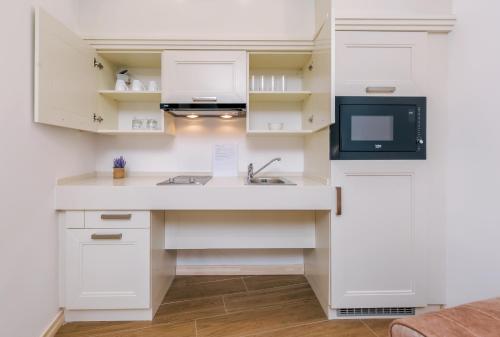 a kitchen with white cabinets and a sink and a tv at Splendido MB Apartments in Tivat
