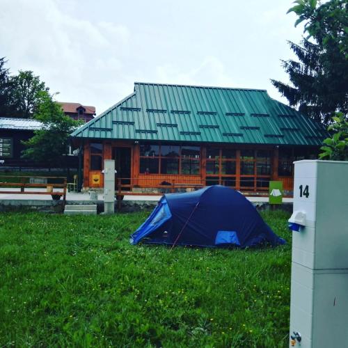 a blue tent in the grass in front of a building at Apartments&Camping ZIP in Kremna