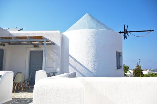 a white building with a white table and chairs at Teoria Paros - Matsas Windmill in Naousa