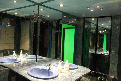 a bathroom with three sinks and a green mirror at Arkady in Słupsk