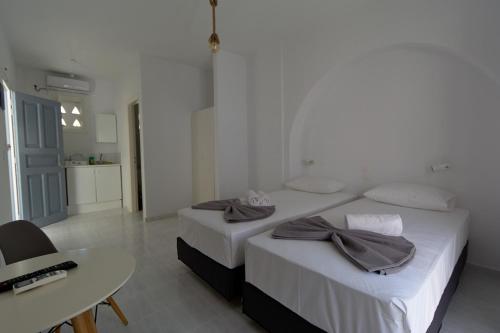 two beds in a room with a table and a desk at Teoria Paros - Matsas Windmill in Naousa