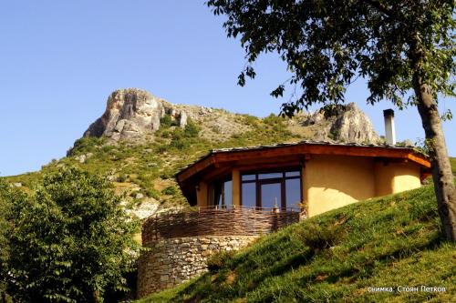 a house on a hill with a mountain in the background at Eco Village Under the Cliffs in Ilindentsi