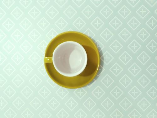 a yellow coffee cup sitting on a plate on a table at O lastraco in Trapani