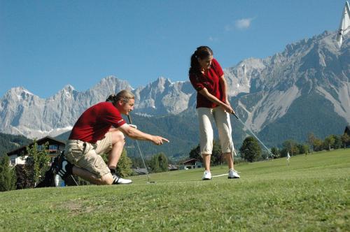 mężczyzna i kobieta grający w golfa na polu w obiekcie Kobaldhof w mieście Ramsau am Dachstein