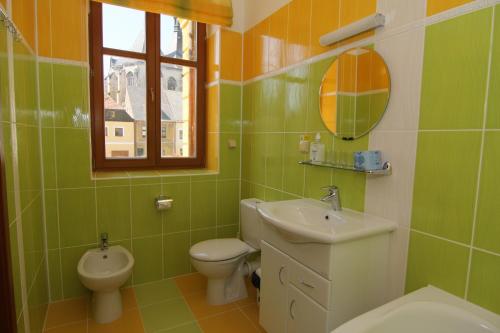 a green bathroom with a toilet and a sink at Hotel U Radnice in Louny