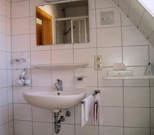 Baño blanco con lavabo y espejo en Gästehaus Waldner, en Alfdorf