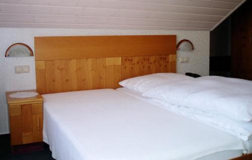 AlfdorfにあるGästehaus Waldnerのベッドルーム1室(白いベッド2台、木製ヘッドボード付)