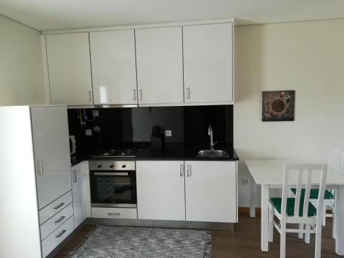a white kitchen with a table and white cabinets at Quinta da Portelada in Peso da Régua