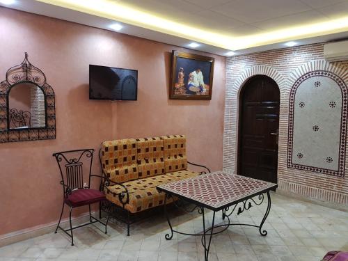 een woonkamer met een bank, een tafel en een tv bij Hotel Salsabil in Marrakesh