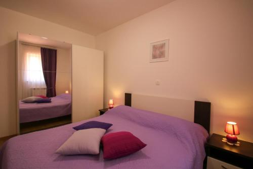 a bedroom with a purple bed with two pillows at Apartments Supra Mare in Rabac