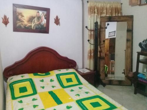 a bedroom with a bed with a yellow and green comforter at Hotel Atenas Jericó in Jericó