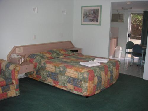 a hotel room with a bed, desk, and chair at Runaway Bay Motor Inn in Gold Coast