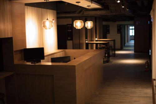 a lobby with a desk with a television and lights at Honest & Warm Hotel in Taoyuan