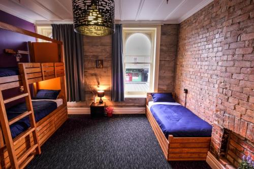a bedroom with two bunk beds and a brick wall at Haka Lodge Auckland in Auckland
