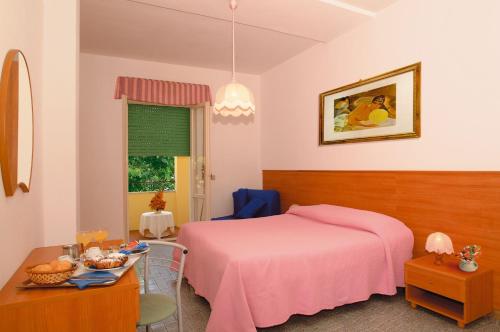 a bedroom with a pink bed and a table at Hotel La Conchiglia in Marciana Marina