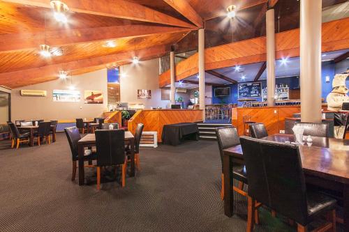 a restaurant with wooden ceilings and tables and chairs at Lakeland Resort Taupo in Taupo
