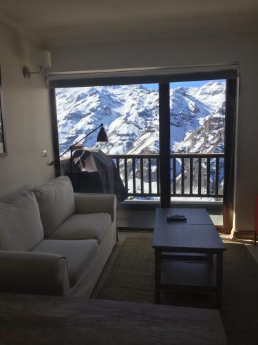 a living room with a couch and a large window with snow covered mountains at Apartment Valle Nevado in Valle Nevado