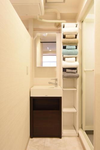 a bathroom with a sink and a mirror and towels at KandoStay EAST TORANOMON in Tokyo