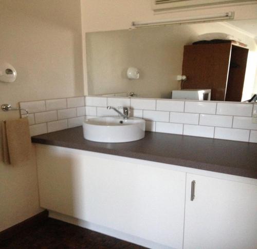 a kitchen counter with a sink and a mirror at Admella Motel in Portland