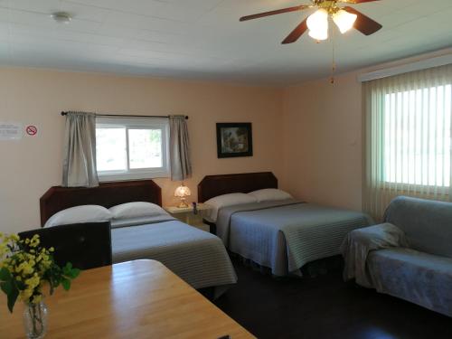 a hotel room with two beds and a couch at Motel Belair in Rigaud