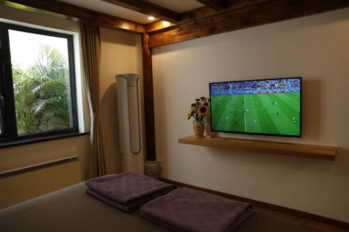 a bedroom with a flat screen tv on the wall at Beijing Downtown Travelotel in Beijing