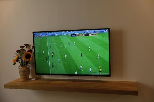 a television on a shelf with a soccer game on it at Beijing Downtown Travelotel in Beijing