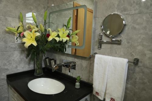a bathroom with a sink and a vase of flowers at Beijing Downtown Travelotel in Beijing