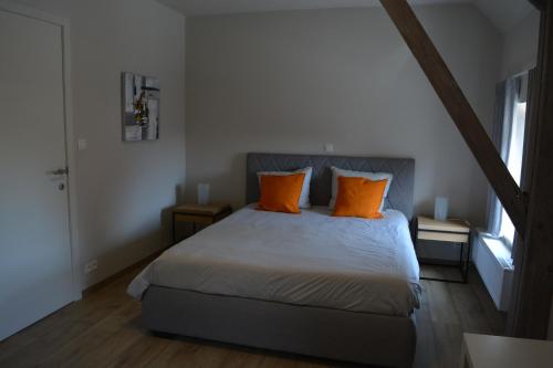 a bedroom with a bed with two orange pillows at Vakantiewoning Den Landman in Nieuwpoort