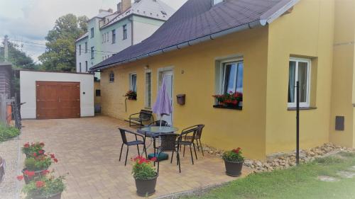 a yellow house with a table and chairs on a patio at Apartmá Andělka in Lipova Lazne