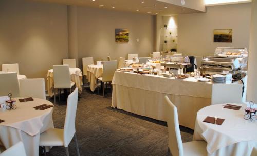 un comedor con mesas blancas y sillas blancas en Expo Hotel Milan, en Parabiago