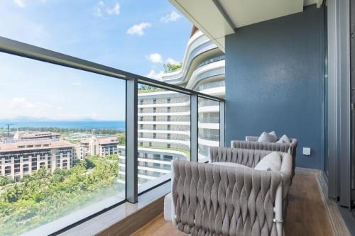 a balcony with two chairs and a large window at Van-Pretty Residence Haitang Bay Sanya in Sanya