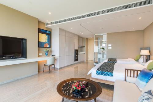 a hotel room with a king sized bed and a living room at Van-Pretty Residence Haitang Bay Sanya in Sanya