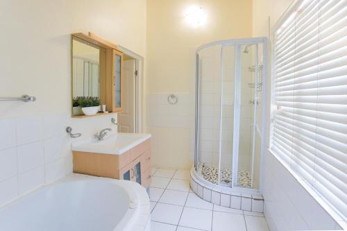 a white bathroom with a shower and a sink at Hathaway Guest House in East London