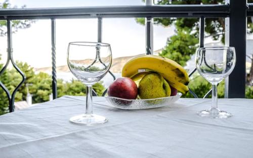 a bowl of fruit on a table with two wine glasses at Mina Apartments in Poros