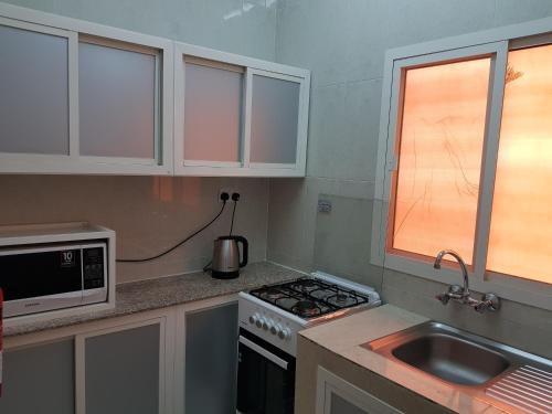 a kitchen with a stove and a sink and a microwave at Today House Suites in Salalah