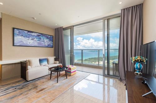 a living room with a couch and a large window at Van-Pretty Residence Haitang Bay Sanya in Sanya