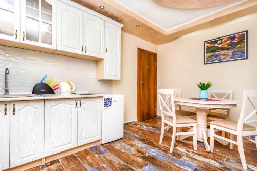 a kitchen with white cabinets and a table and chairs at Apartments Amigo in Kotor