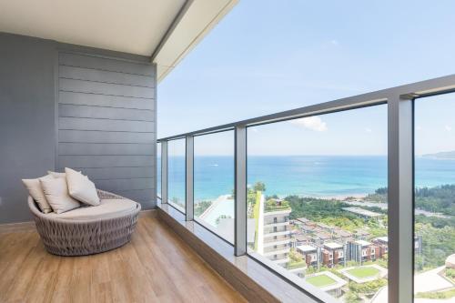 a balcony with a chair and a view of the ocean at Van-Pretty Residence Haitang Bay Sanya in Sanya