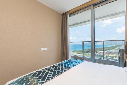 a bedroom with a bed and a large window at Van-Pretty Residence Haitang Bay Sanya in Sanya