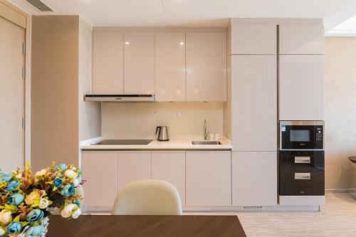 a kitchen with white cabinets and a table with a vase of flowers at Van-Pretty Residence Haitang Bay Sanya in Sanya