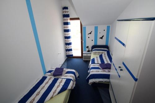 two beds in a small room with a window at Apartments Sersic in Baška